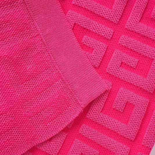Close-up of a long knitted cardigan set featuring vibrant pink fabric and textured patterns