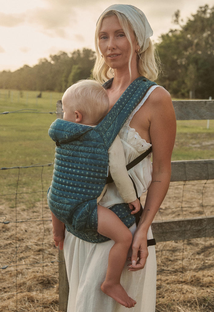 Spell x Bumpsuit Armadillo Baby Carrier in Vintage Blue cotton, worn front-facing outdoors