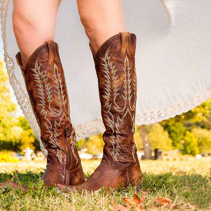 Stylish embroidered western boots for women with intricate designs in a beautiful outdoor setting