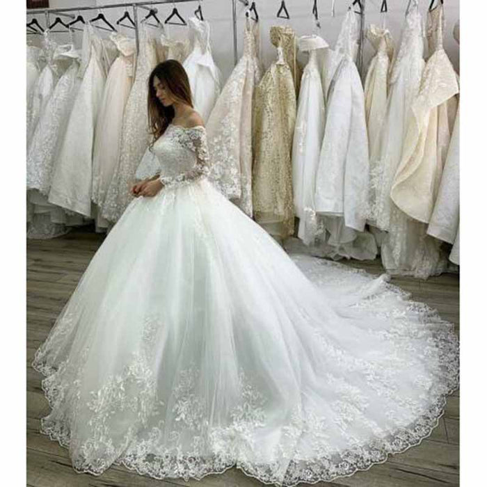 Elegant lace beach wedding dress with sleeves featuring a flowing skirt and intricate floral details