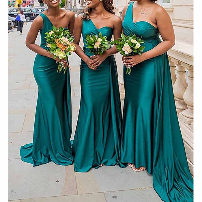 Elegant one shoulder satin bridesmaid dress in green, worn by three bridesmaids holding bouquets