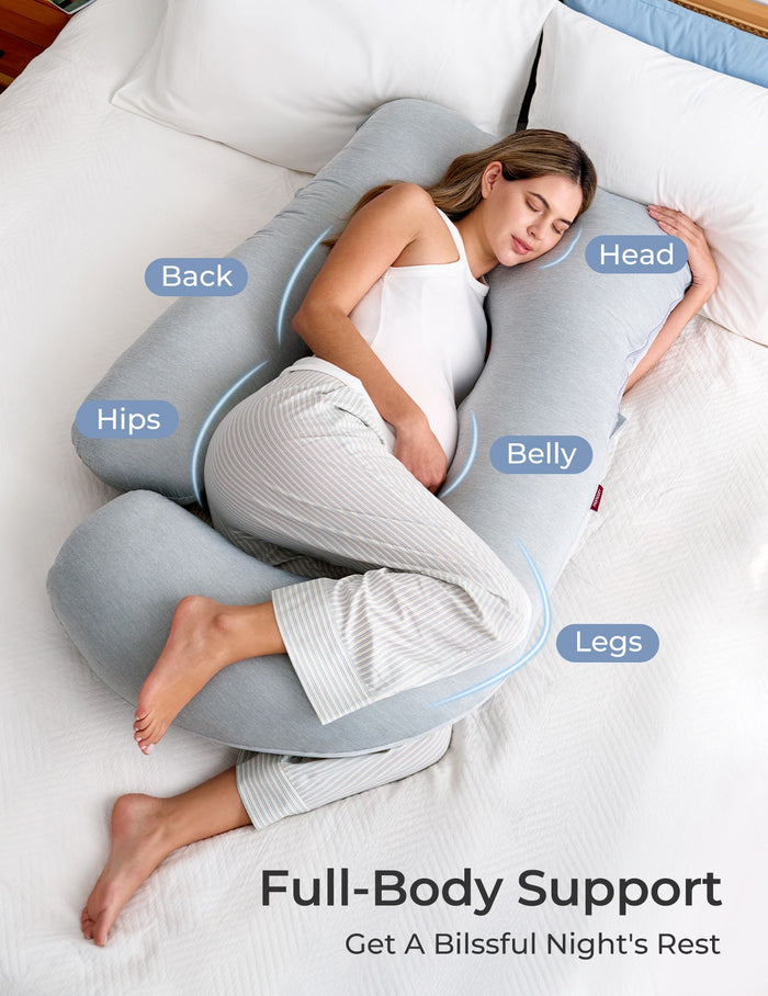 Pregnant woman resting on gray U-shaped maternity pillow, full body support for pregnancy, restful sleep, Momcozy