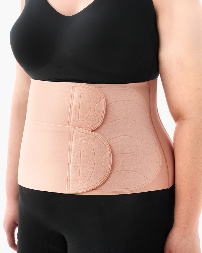 Momcozy Ergowrap Postpartum Belly Band in oyster pink color, worn by a woman for postpartum support.