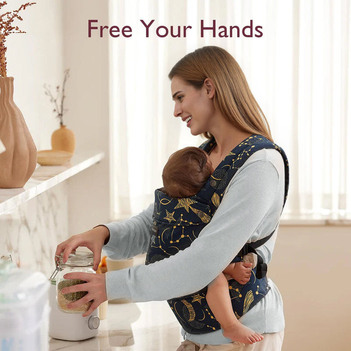 Momcozy PureHug navy blue baby carrier with star pattern, hands-free design. Mother babywearing while performing daily tasks.