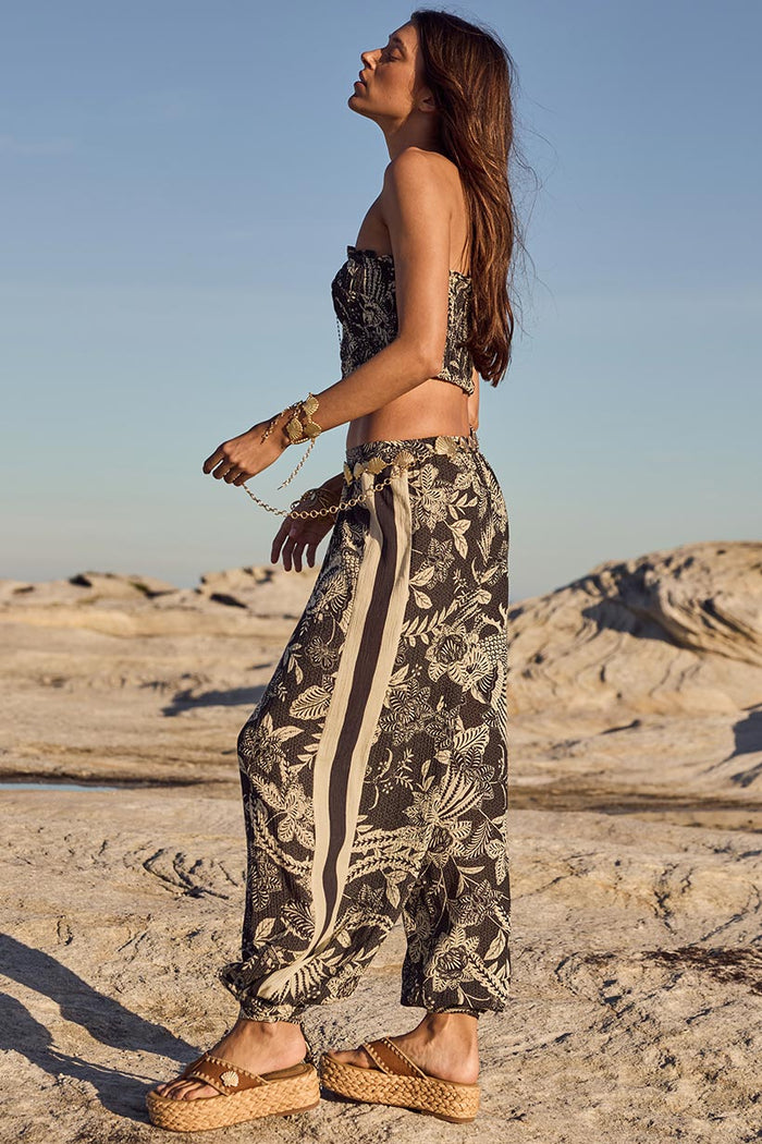 Side view of Volcano Goddess Harem Pant, showing side stripe detail and tie hem cuff, styled on rocky coastal landscape