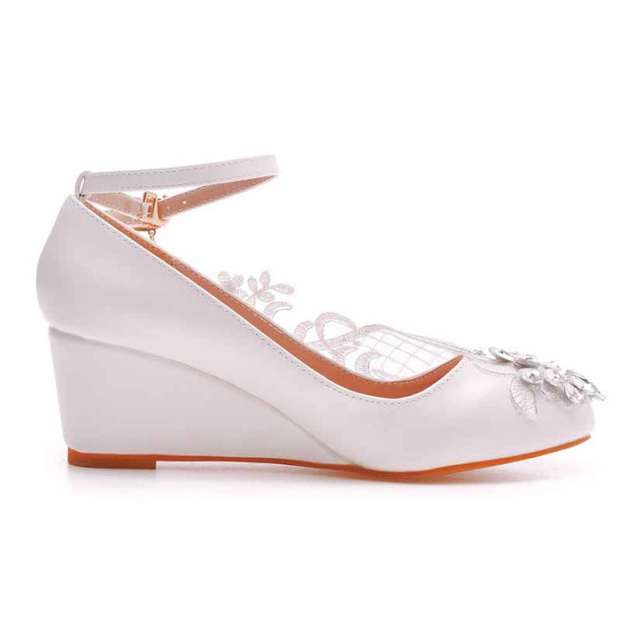 Elegant white wedge bridal sandals with floral embellishments and an ankle strap for a perfect wedding day